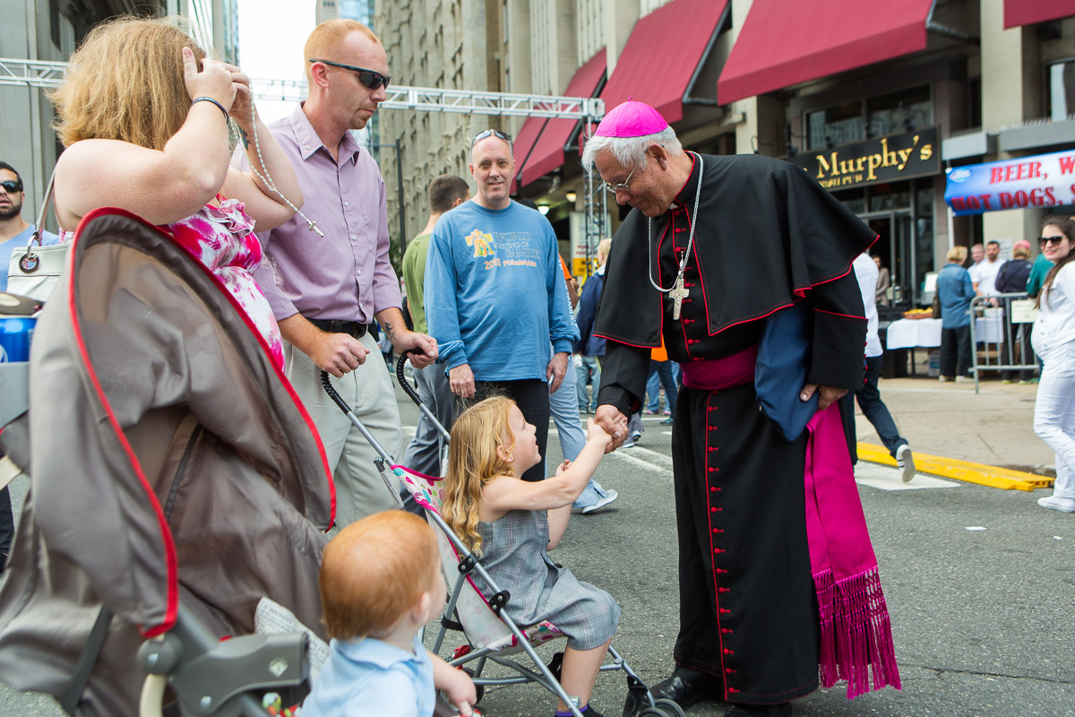 Father Fausto Trávez, right, from Quito, Ecuador, greets a child during the visit of Pope Francis to Philadelphia.