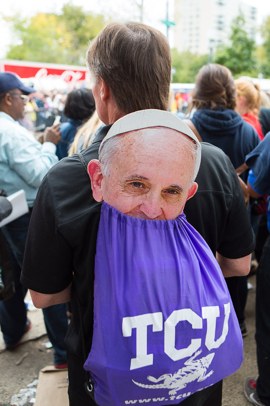 A cardboard cutout of Pope Francis peeks out of a man's backpack during mass led by the Pope on the Ben Franklin Parkway in Philadelphia.