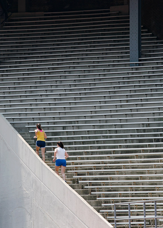 Erin Katims, in yellow shirt, a former tennis coach, and Jessy Smith, a former assistant gymnastics coach, both for the University of Pa., exercise at Franklin Field on the campus in Philadelphia by doing stair repetitions.