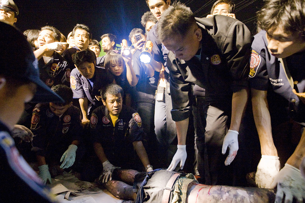 Volunteers crowd around a dead body in Bangkok.