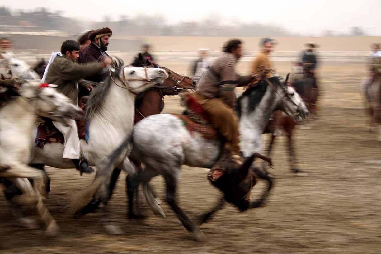 A man on a horse carries a goat carcass across a pitch during a buzkashi match in Kabul, Afghanistan. 