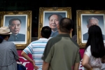 People look at portraits of former Chinese leaders Zhou Enlai, left, Mao Zedong, center, and Liu Shaoqi displayed in a shop, Beijing.