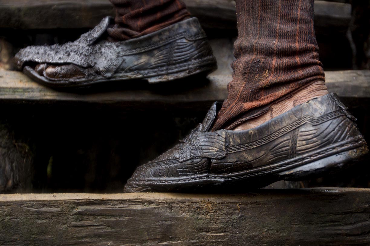 A labourer wearing tattered shoes, walks up from a mining pit in the Jaintia Hills. 
