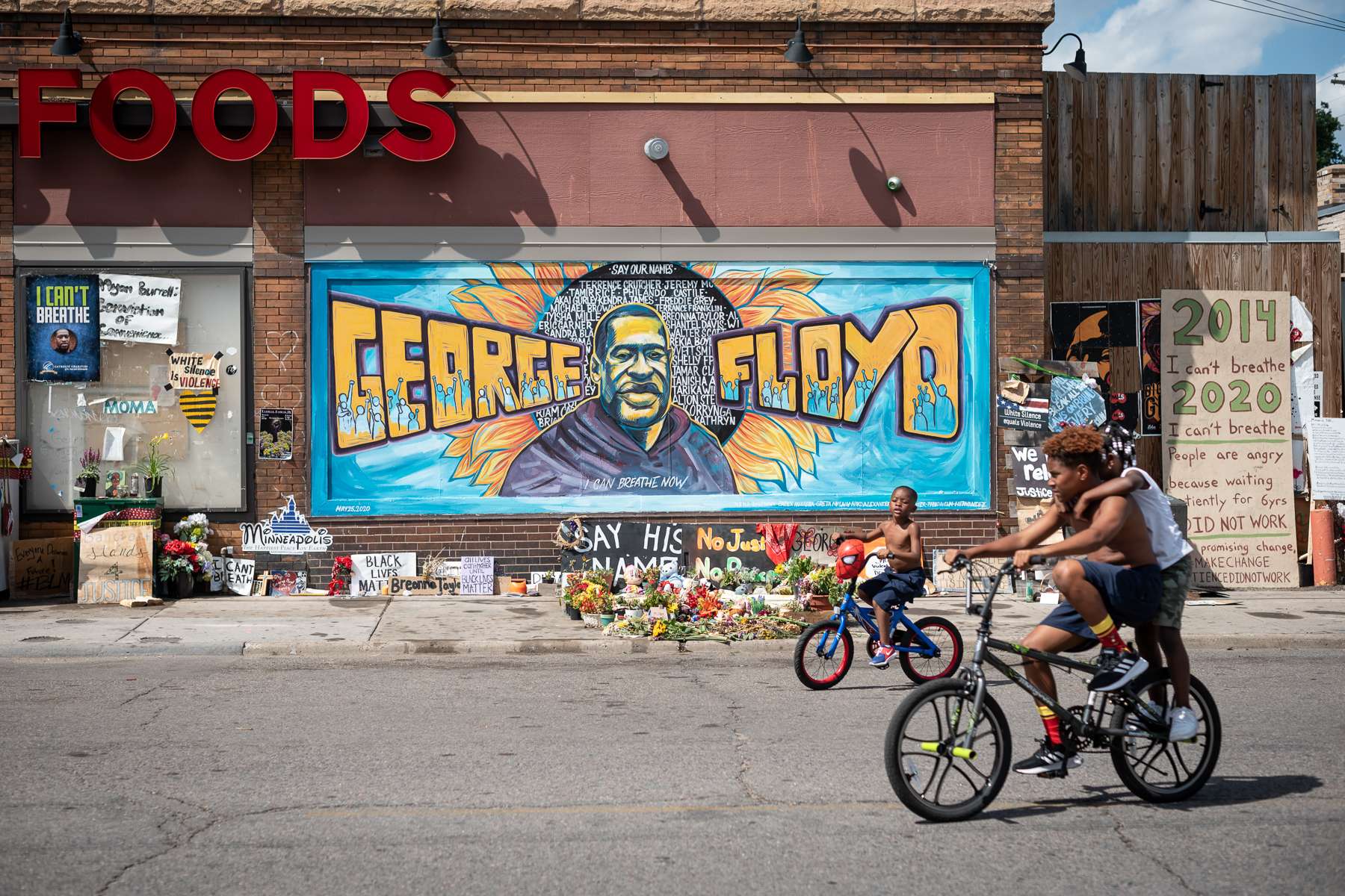 Young boys ride by one of the murals at the George Floyd Memorial site in Minneapolis, MN on July 17, 2020.