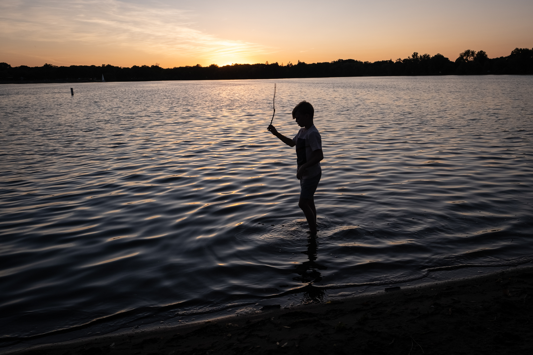 MINNEAPOLIS, MN - AUGUST 13, 2021: Finley Stoks, 9, of St. Paul, MN, plays in the water at Lake Nokomis on a clear night in Minneapolis. Recent wildfires in Canada brought some of the worst air quality to Minneapolis this summer, impacting what the Stoks family was able to do outside.