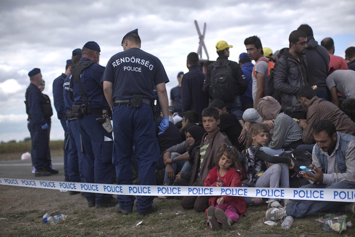 Hungarian police officers block a group of refugees on a road, Roszke, Hungary, Sept. 7, 2015. 