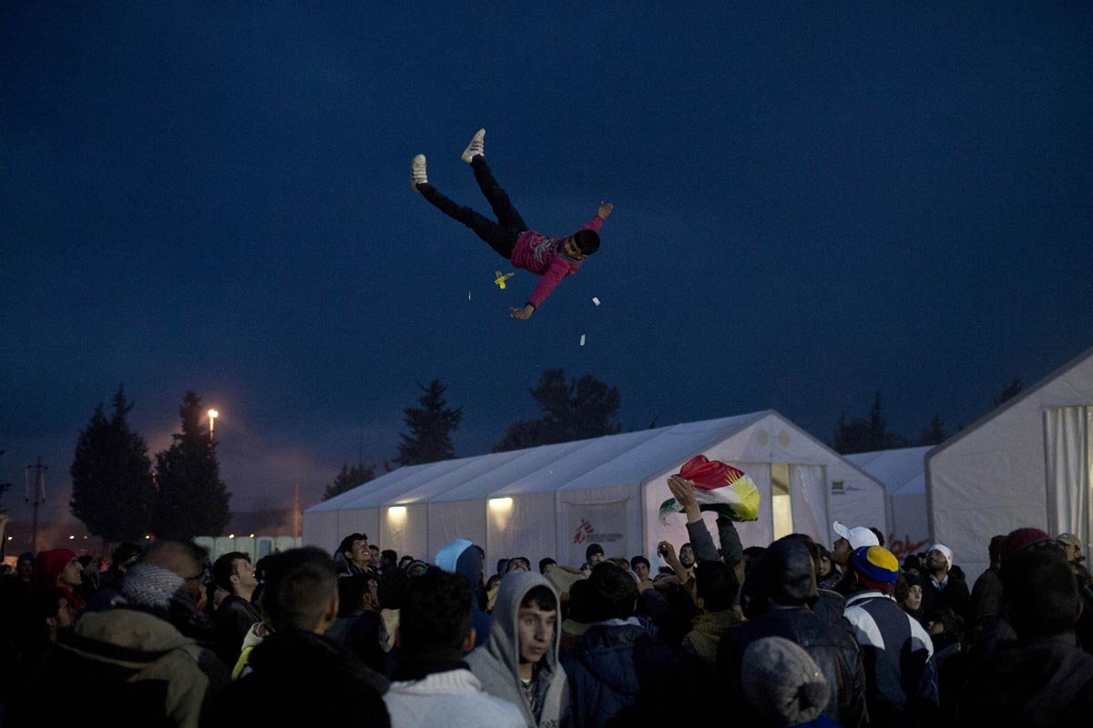 A man is thrown into the air during a celebration at the refugee camp in Idomeni, Greece, March 27, 2016. 