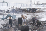 People take a bath while heating water in an old oil drum, Belgrade, Serbia, Jan. 19, 2017.