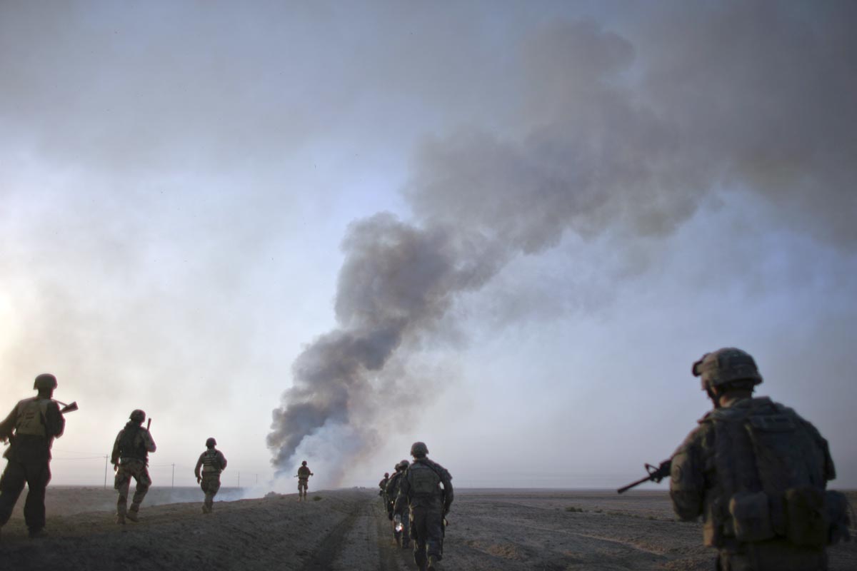 U.S. army soldiers from Fox Troop, Sabre Squadron, 3rd Armored Cavalry Regiment, move in formation after they set a deserted village on fire, outskirts of Balad Ruz, Diyala province, Iraq, 2008.