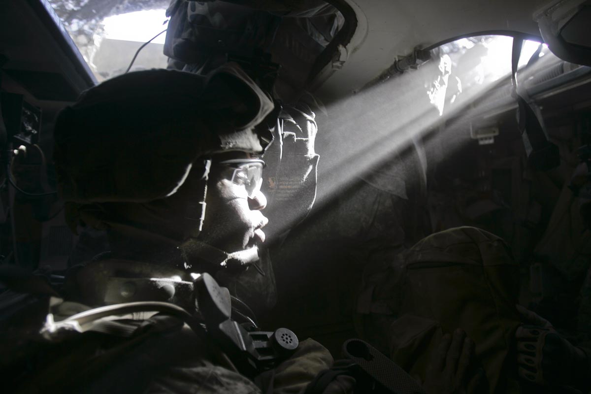 A ray of light hits the face of a U.S. army soldier from Blackfoot Company, 2nd Battalion, 23rd Infantry Regiment, as he sits in a Stryker armored vehicle, Diyala province, Iraq, 2007.