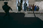 A family stand outside their home as U.S. army soldiers from Able Company, 4th Battalion, 9th Infantry Regiment, patrol their street, Baqouba, Iraq, 2007. 