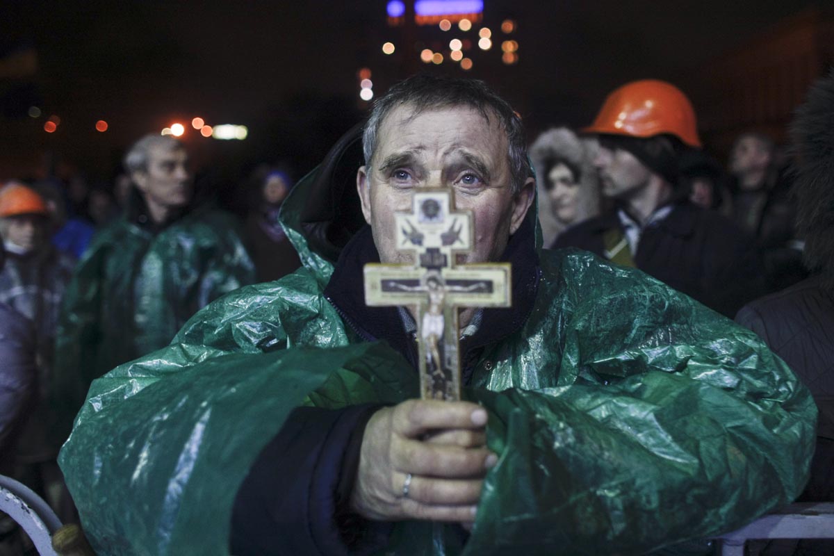 A man holds a cross as he prays, Kiev, Ukraine, Feb. 20, 2014. 