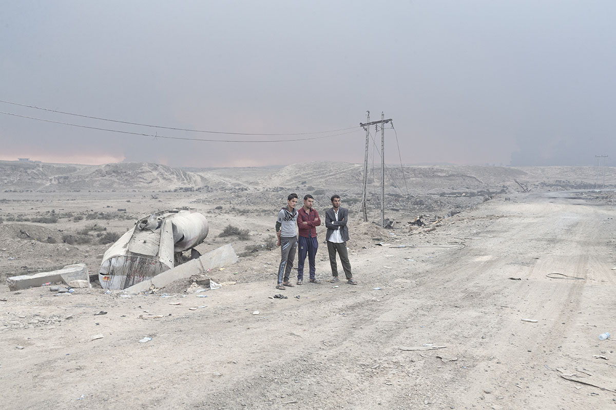 Three men stand on the side of a road, Qayara, south of Mosul, Iraq, Oct. 23, 2016.