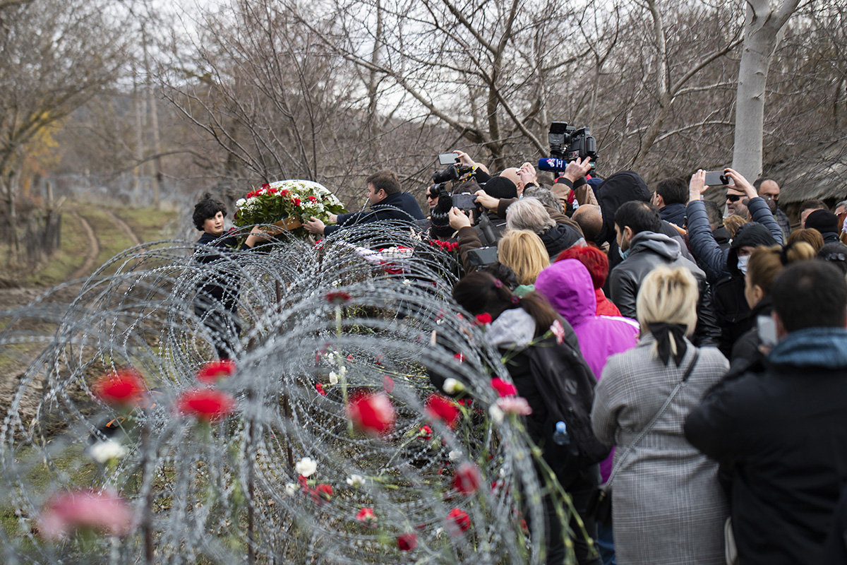 Local people and journalists stand and pass flowers over to Data Vanishvili's grandson Dato Vanishvili, 14, as he stands in Georgia's breakaway region of South Ossetia, during 88-year-old Data's funeral in the village of Khurvaleti, Georgia, March 22, 2021. Data Vanishvili, then already in his eighties, became a symbol of this fearful frontier existence after he, his wife and son woke up in 2013 to find a barbed-wire fence had been erected in the night, putting their home on the Ossetian side of the boundary. Vanishvili became well-known in Georgia for staying put and defiantly speaking out publicly. Despite the risks, he would cross the boundary to get his pension and to buy food. On his deathbed at the age of 88, his final words to his wife were a plea not to abandon their home. {quote}Do not leave the house, do not go anywhere, sit by the stove, the Georgians will help you,{quote} his family recall him saying. He was buried in the breakaway region of South Ossetia. 