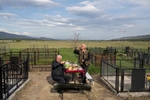 An Ossetian person (L) and a Georgian person (R) pay respects to a deceased relative of theirs, as they have a drink together at a cemetery in the village of Khurvaleti, Georgia, April 29, 2019.       