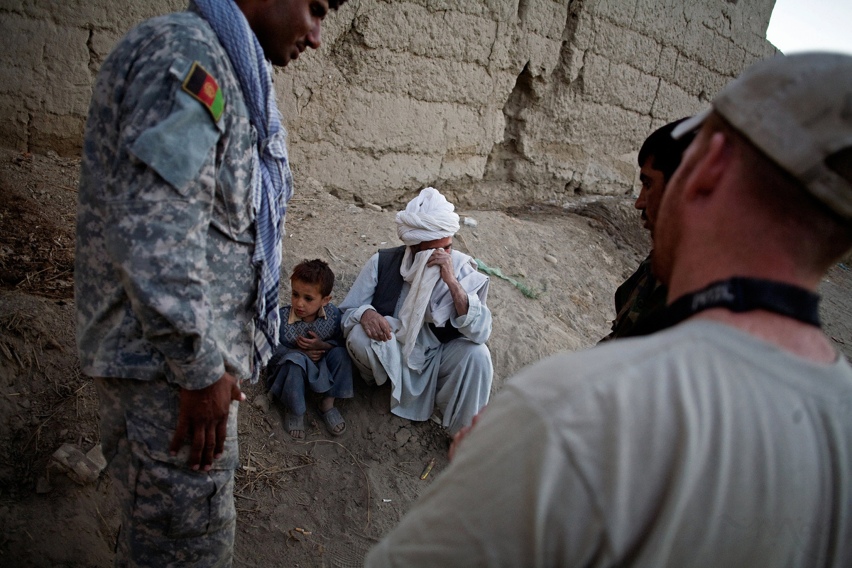American soldiers watches as a villager who lost his house after the Americans dropped bombs on it the night before sheds tears. The villager alerted the Americans to the fact that the Taliban where holed up in his home. The Americans then bombed the home the following night. The man now was asking for compensation as everything he owned was destroyed in the attack. He now lives outside of town in a tent and was asking for food and clothing for this children.