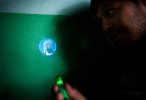 Burhan Amin, 26, shines a light from the back of a cigarette lighter that projects the image of Osama bin Laden that he purchased from a shop in the village of Khenj, Afghanistan on Friday, October 26, 2007. Ten years after the September 11th attack on the United States bin Laden was killed in Pakistan. 