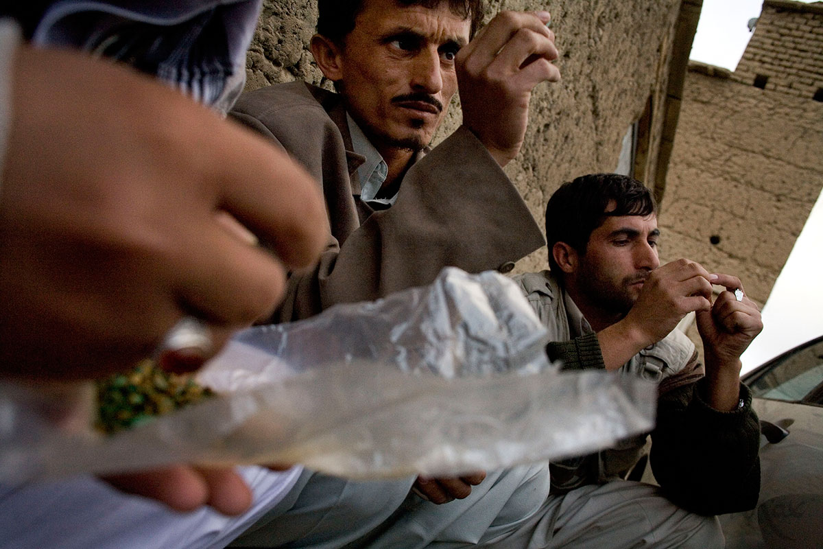 Emerald buyers from Kabul, Hiatullah, left, and Gulalam, right, look at a pocketful of emeralds brought down the mountain in the village of Khenj, Afghanistan on Friday, October 26, 2007. Most miners keep their emeralds in a plastic package. Usually the partners in a mine will weigh, count, then wrap the emeralds they find, signing the wrapping to insure they all agree on what was found. Then the package is opened again when it reaches the village and is sold. 