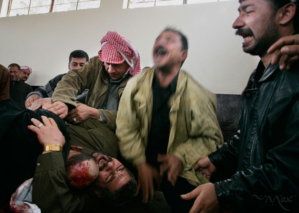 Karim Rahim Judi Yacoubi, bottom left, holds the corpse of his dead brother, Naim, 37, as he and his brothers, Salim, center in a green jacket, and Hadi, right, scream out in grief in the washroom where Naim’s body was being prepared for burial in the Najaf cemetery. Naim was killed during a suicide bombing on Election Day in Baghdad. 