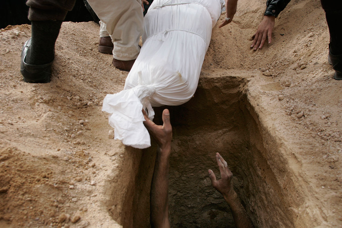 A gravedigger reaches for the body of, Naim Rahim Judi Yacoubi, 37, to lower him into his grave. While many Iraqis were joyous to have the opportunity to vote, others paid the ultimate price. 