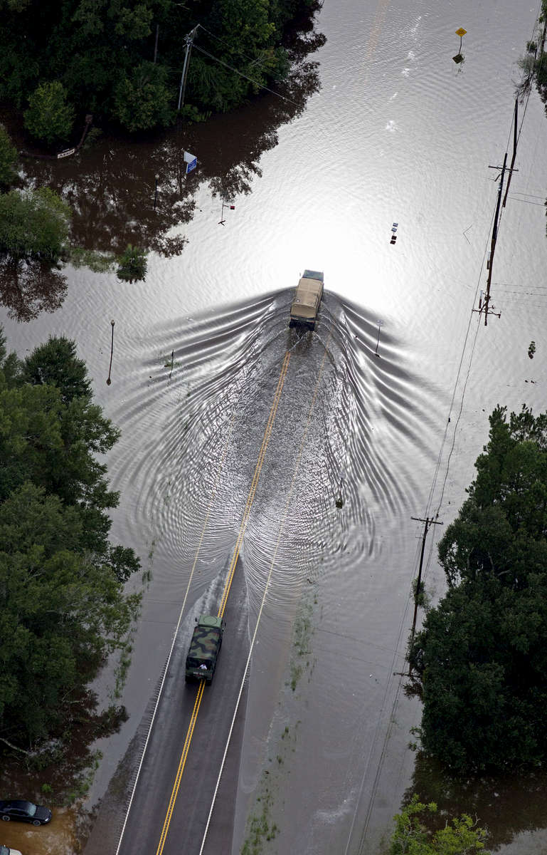 In this aerial photo over Robert, La. USA, Louisiana Army National Guard vehicles drive on flooded U.S. Route 190 after heavy rains inundated the region, Robert,  La. USA, Saturday, Aug. 13, 2016. Louisiana Gov. John Bel Edwards says more than 1,000 people in south Louisiana have been rescued from homes, vehicles and even clinging to trees as a slow-moving storm hammers the state with flooding. (AP Photo/Max Becherer)