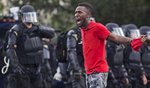 A protester yells at police in front of the Baton Rouge Police Department headquarters after police arrived in riot gear to clear protesters from the street in Baton Rouge, La. USA, Saturday, July 09, 2016. The starting point of Saturday's demonstration was the convenience store where 37-year-old Alton Sterling, a black CD seller, was captured on video being shot and killed by white police on July 5th. Protesters then fanned out to the Baton Rouge Police Department and the State Capitol. (AP Photo/Max Becherer)
