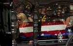 East Baton Rouge Parish Sheriff Sid  Gautreaux and his wife are reflected in the glass of the horse-drawn carriage carrying the casket of East Baton Rouge Sheriff's Deputy Brad Garafola at the Istrouma Baptist Church in Baton Rouge, La. USA, Saturday, July 23, 2016. Garafola is survived by a wife and four children; sons ages 21 and 12; and daughters ages 15 and 7. {quote}When that assassin's bullet targeted our heroes — and he was an assassin — he not only targeted them, he targeted the city. He targeted his country, and it touched the soul of the entire nation,{quote} Vice President of the United States Joe Biden said at a memorial for the three slain officers six days later. (Max Becherer/AP)