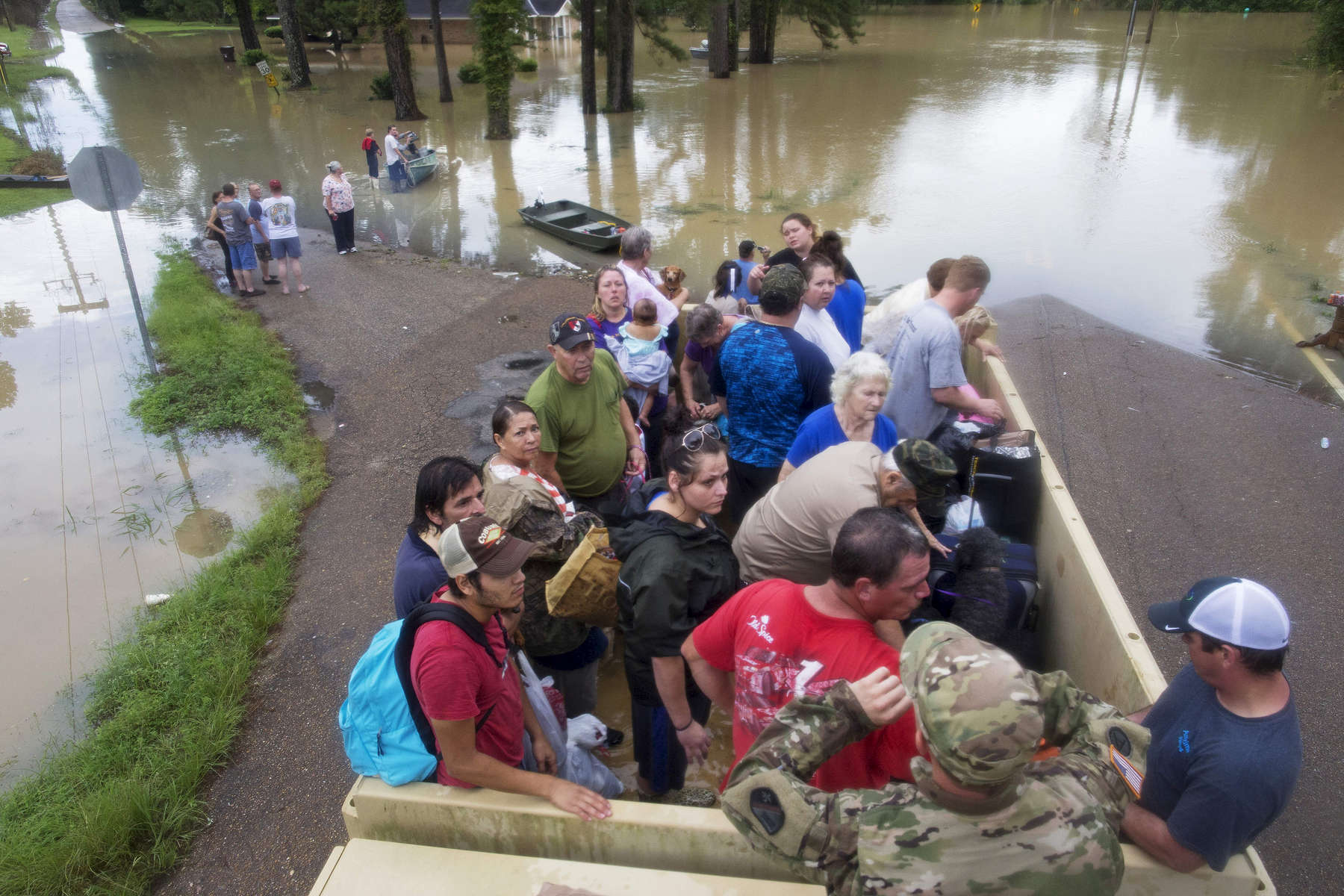 Sgt. Brad Stone of the Louisiana Army National Guard gives safety instructions to people loaded on a dump truck after they were stranded by rising flood water near Walker, La. USA, Sunday, Aug. 14, 2016. Rescuers have evacuated more than 20,000 people since the flooding started Friday and more than 10,000 people were in shelters as of late Sunday, according to Louisiana Gov. John Bel Edwards. (AP Photo/Max Becherer)