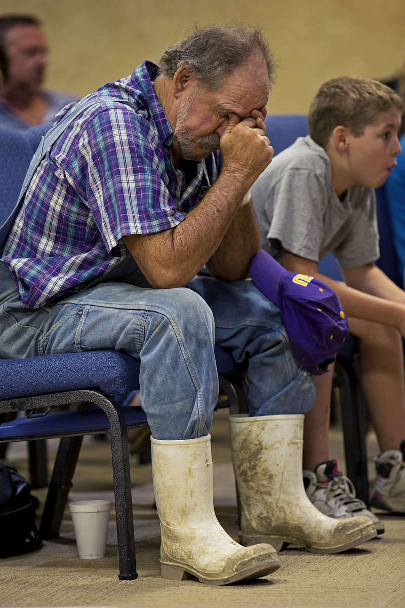 Robert Miller, 66, prays during service at the South Walker Baptist Church in Walker, La. USA, Sunday, Aug. 21, 2016. Miller had six family members in his home when the flood struck and helped them flee the home while he stayed behind to care for his dogs. Miller wounded his left wrist with a saw while trying to clean up the flood damage. (AP Photo/Max Becherer)