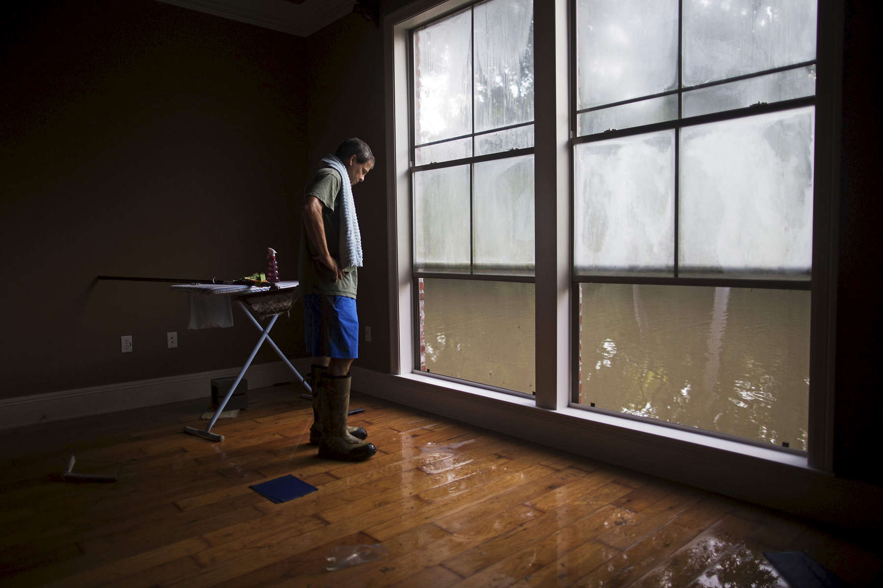 David Key looks at water out of his master bedroom windows in his flooded home in Prairieville, La. USA, Tuesday, Aug. 16, 2016. Key, an insurance adjuster, fled his home as the flood water was rising with his wife and three children and returned Tuesday to assess the damage. Mike Steele, spokesman for the Governor's Office of Homeland Security and Emergency Preparedness, said 102,000 people have registered for federal aid. (AP Photo/Max Becherer)