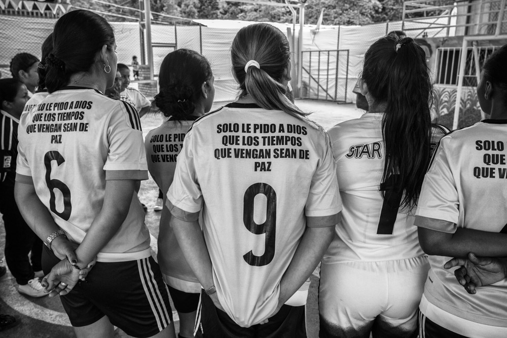 September 25, 2017. La Elvira, Cauca, Colombia. The back of s shirt reads “I only pray to God that the times to come will bring peace” of one of the members of the members of the team from the nearby villages La Esperanza (in pink) as they gather to hear the referee of the tournament.