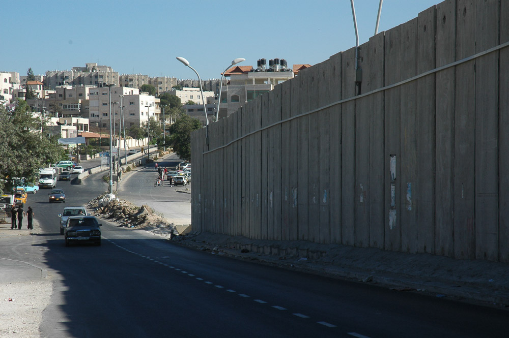 A Ram, a Jerusalem suburb, is separated from Jerusalem by a 26 ft concrete wall. It snakes in and out separating houses, and families.