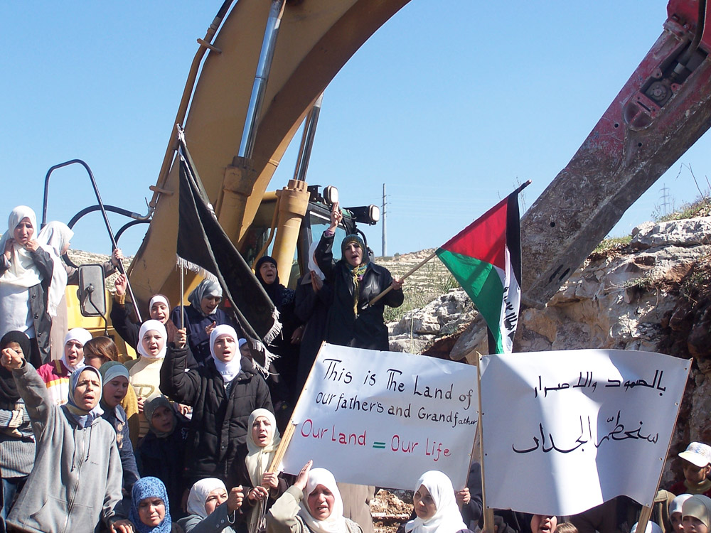 Women blocking the bulldozers from constructing the wall.