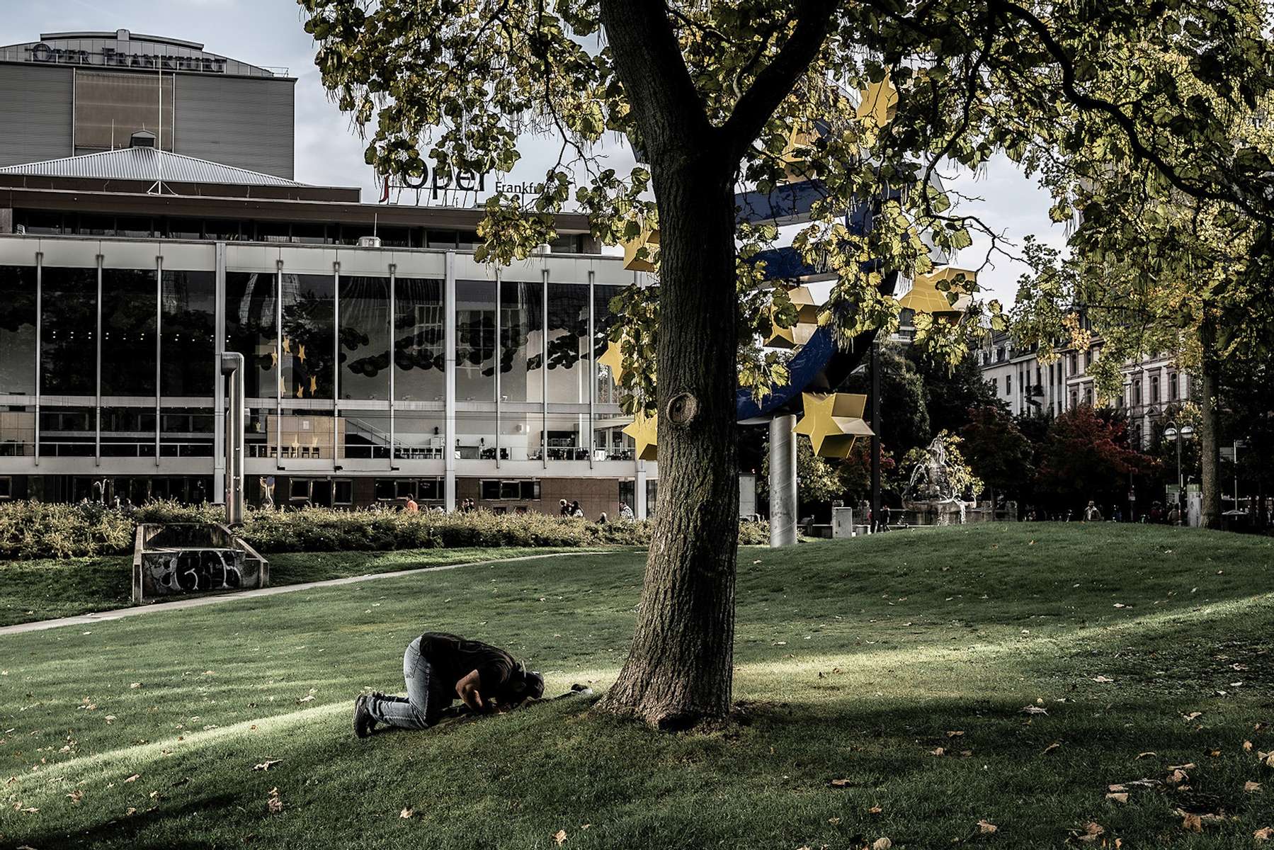 In the afternoon a muslim man is praying under a tree in downtown Frankfurt