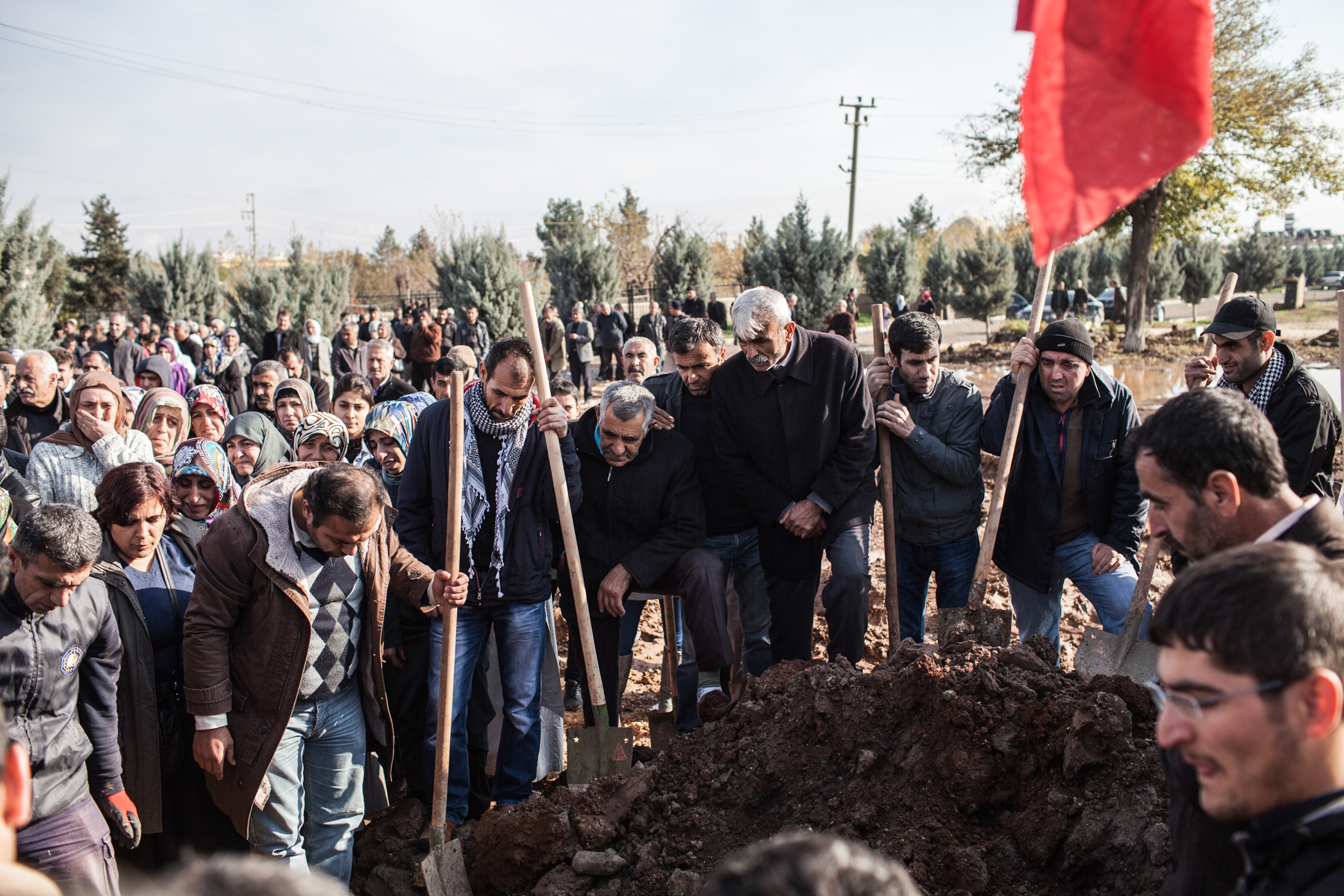 People are seen crying and lowering a casket into a freshly dug grave on a cemetary in the city of Diyarbakir. It is the burial of a female fighter of the Kurdish freedom movement PKK. 