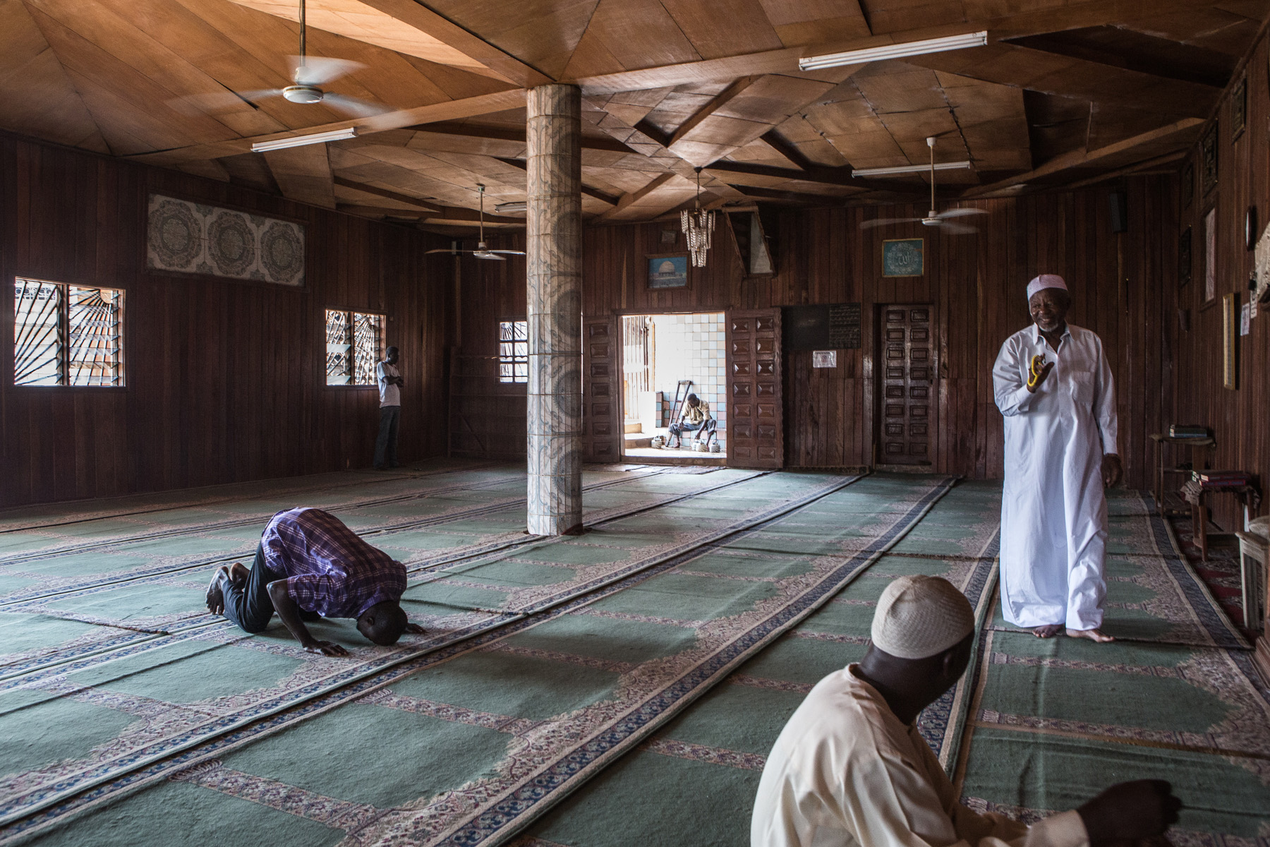 Muslim men are praying and sitting inside a mosque in Cameroon's capital Yaounde. 