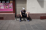 A man with a bandage around his head is sitting in front of a building in downtown Offenbach