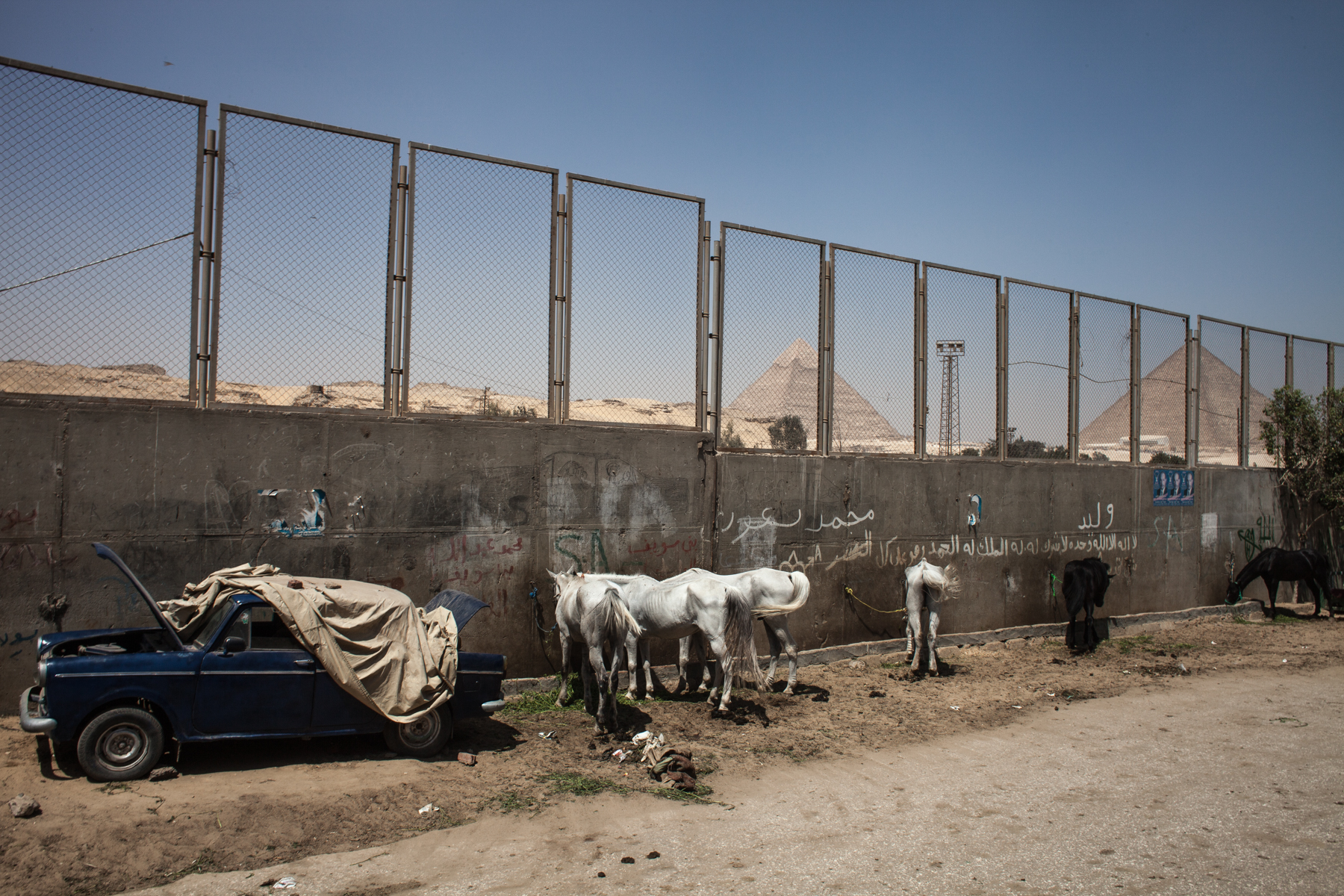 Behind the wall in the Egyptian town of Giza the famous pyramids are seen in the background