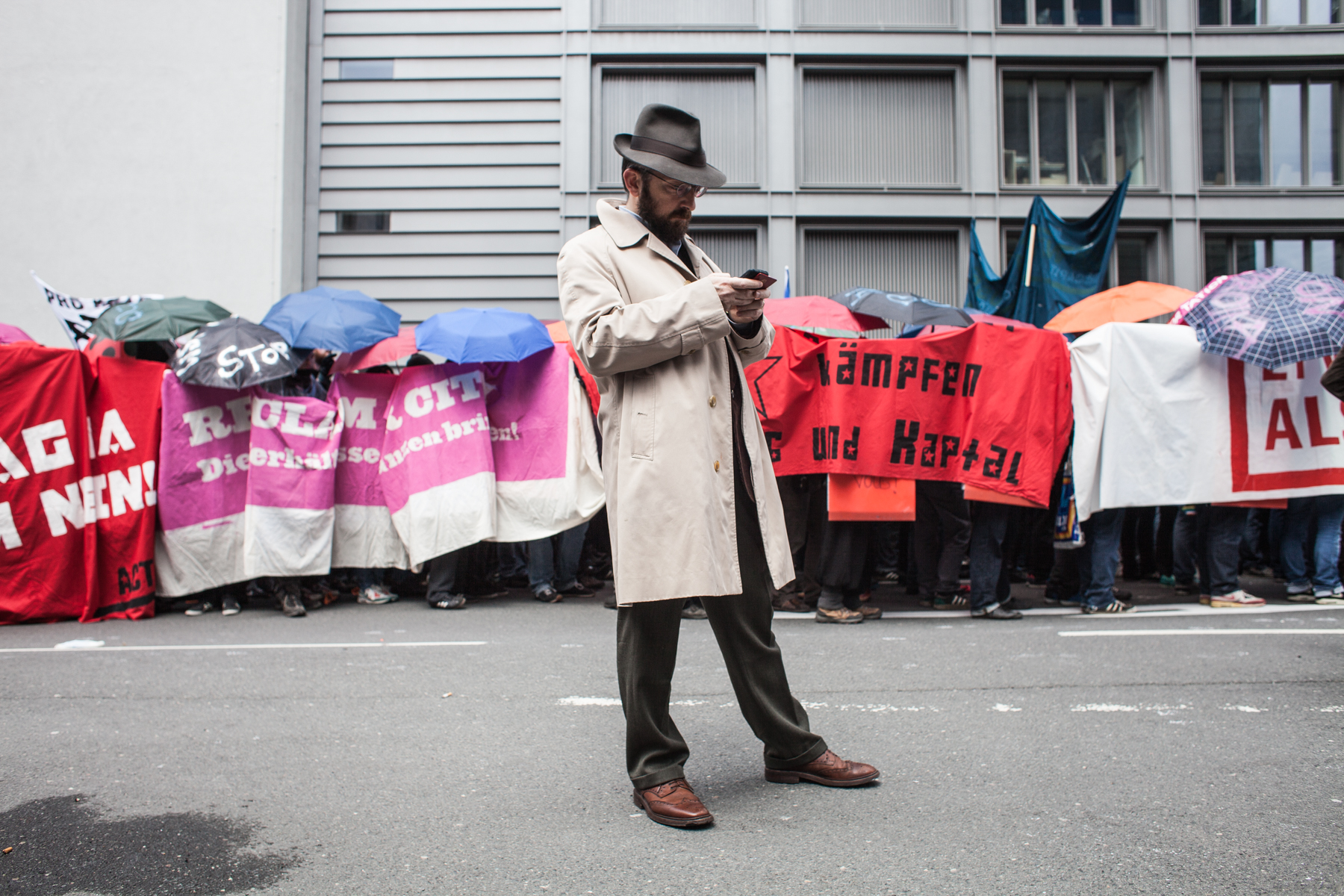 A man dressed with a trench coat is standing in front of a row of demonstrating people during the Blockupy protests in March 2013 in Frankfurt