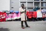 A man dressed with a trench coat is standing in front of a row of demonstrating people during the Blockupy protests in March 2013 in Frankfurt