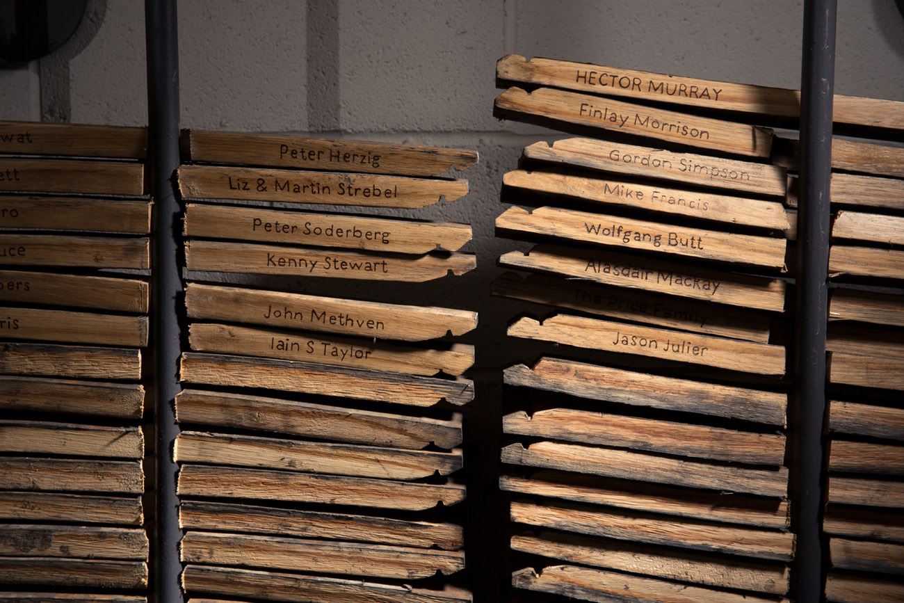 Harris whisky barrel staves stacked against a wall. cask staves with names on.