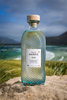 bottle of harris gin sitting on the sand on the beach on a sunny day