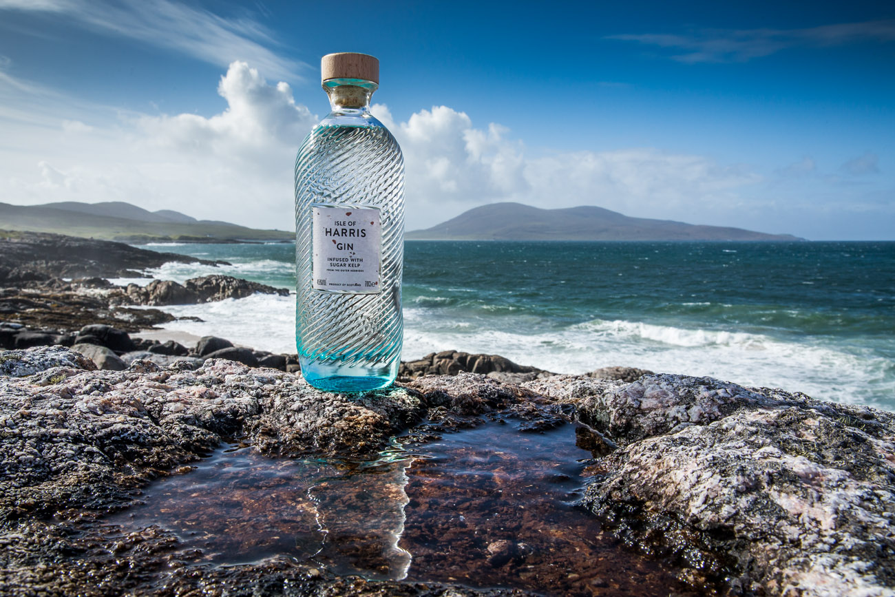a bottle of Harris gin sitting on the rocks by the sea on isle of harris