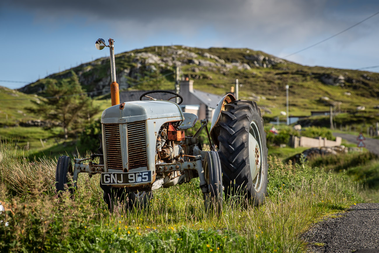 beautiful old tractor by the side of a road in evening light on the isle of harris. 
