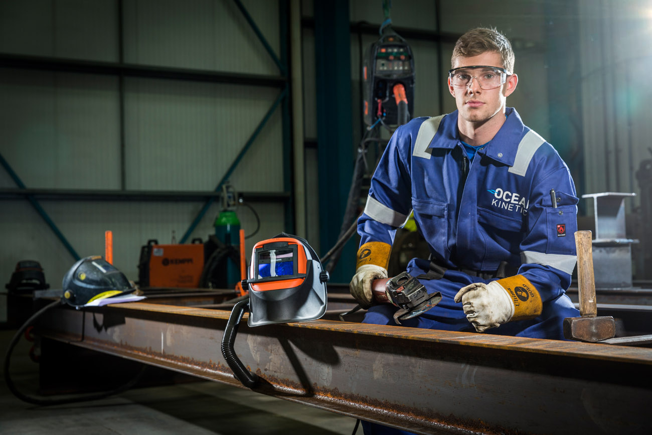Environmental portrait of young apprentice at work in a factory