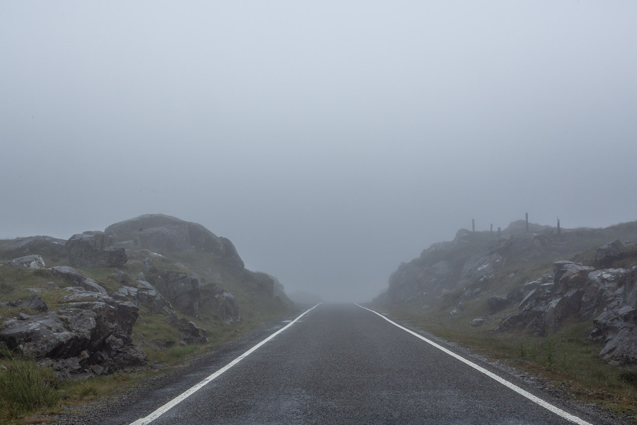 misty single track road with hills either side n isle of harris. road dissapearing into the fog