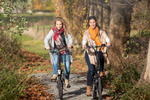 two women cycling through a beautiful forest in autumn