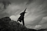 Coneman leaping off rocks in the mountains. Black and white photograph