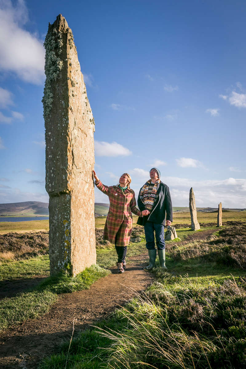 Historic Scotland  - ring of Brodgar on Orkney with a woman touching a standing stone