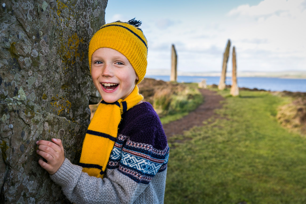 Historic Scotland  - smiling boy by a standing stone at ring of Brodgar on Orkney